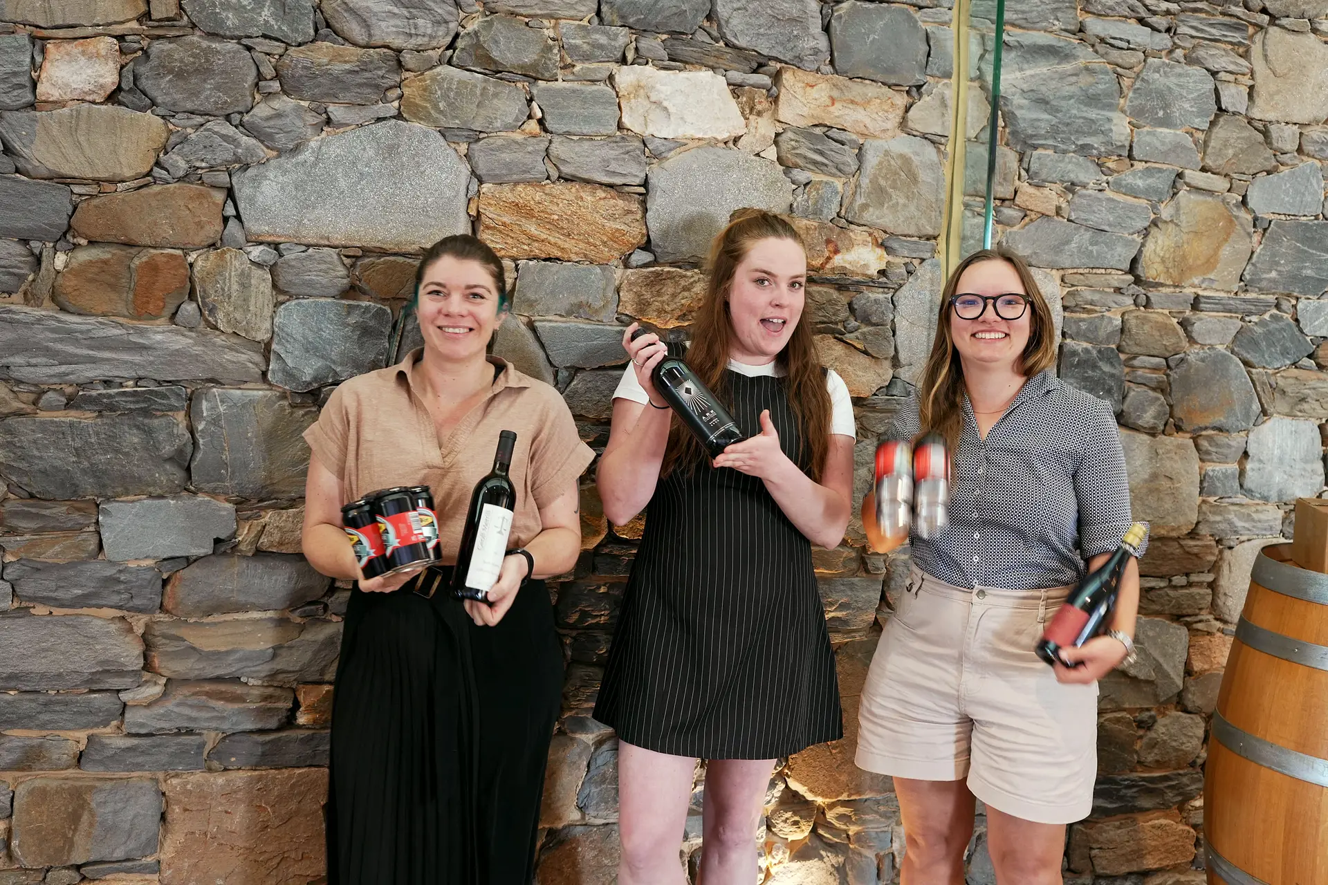 The Barossa Bowl podium — Piper de Raadt, Topsi W. and Susanne Wuerfl — laughing against the stone wall, prize bottles held up.
