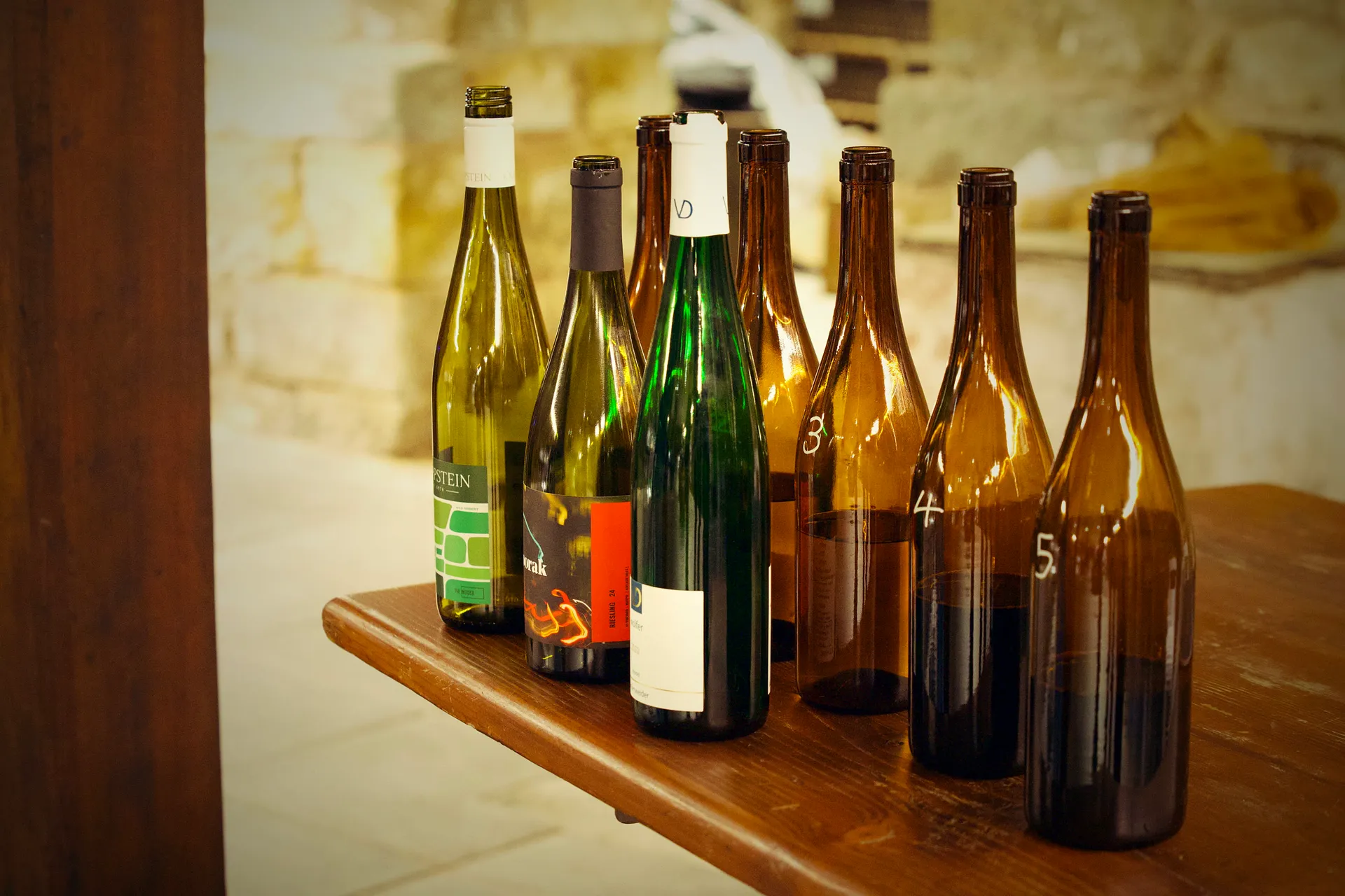 The five Clare Cup bottles standing revealed on a timber ledge, chalk numbers still on the amber service bottles.
